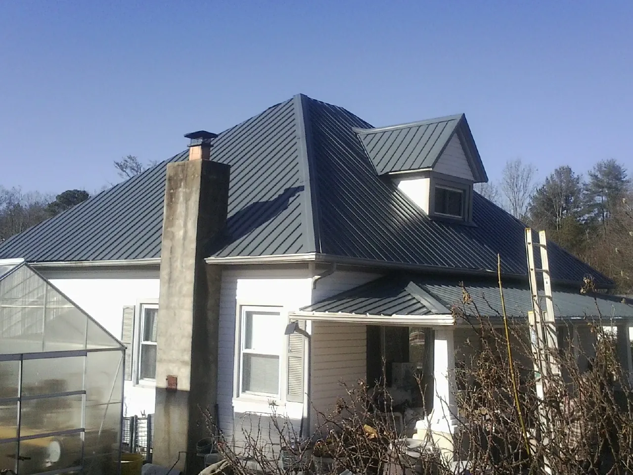 Dark blue standing seam metal roof on a white farmhouse with dormer — Slate & Tile Roof Repair by Roofing Brothers in Wyndmere