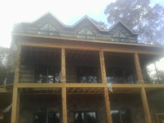 Dormers and porch framing on a large log home under construction — Roof Coating work by our crew in Wyndmere