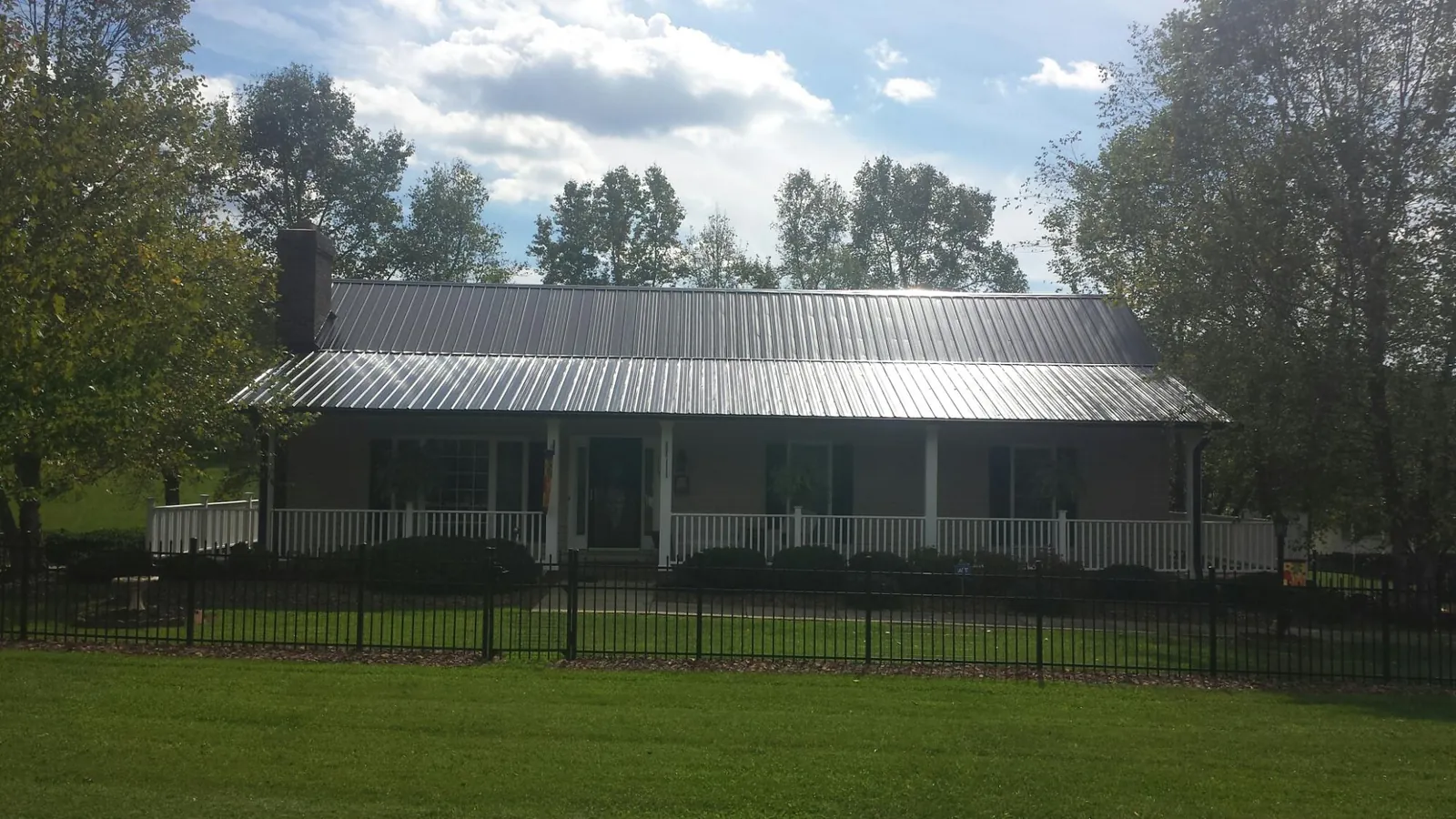 Gray metal roof on a brick ranch with a full width front porch — Gutter Guard Installation work by our crew in Wyndmere