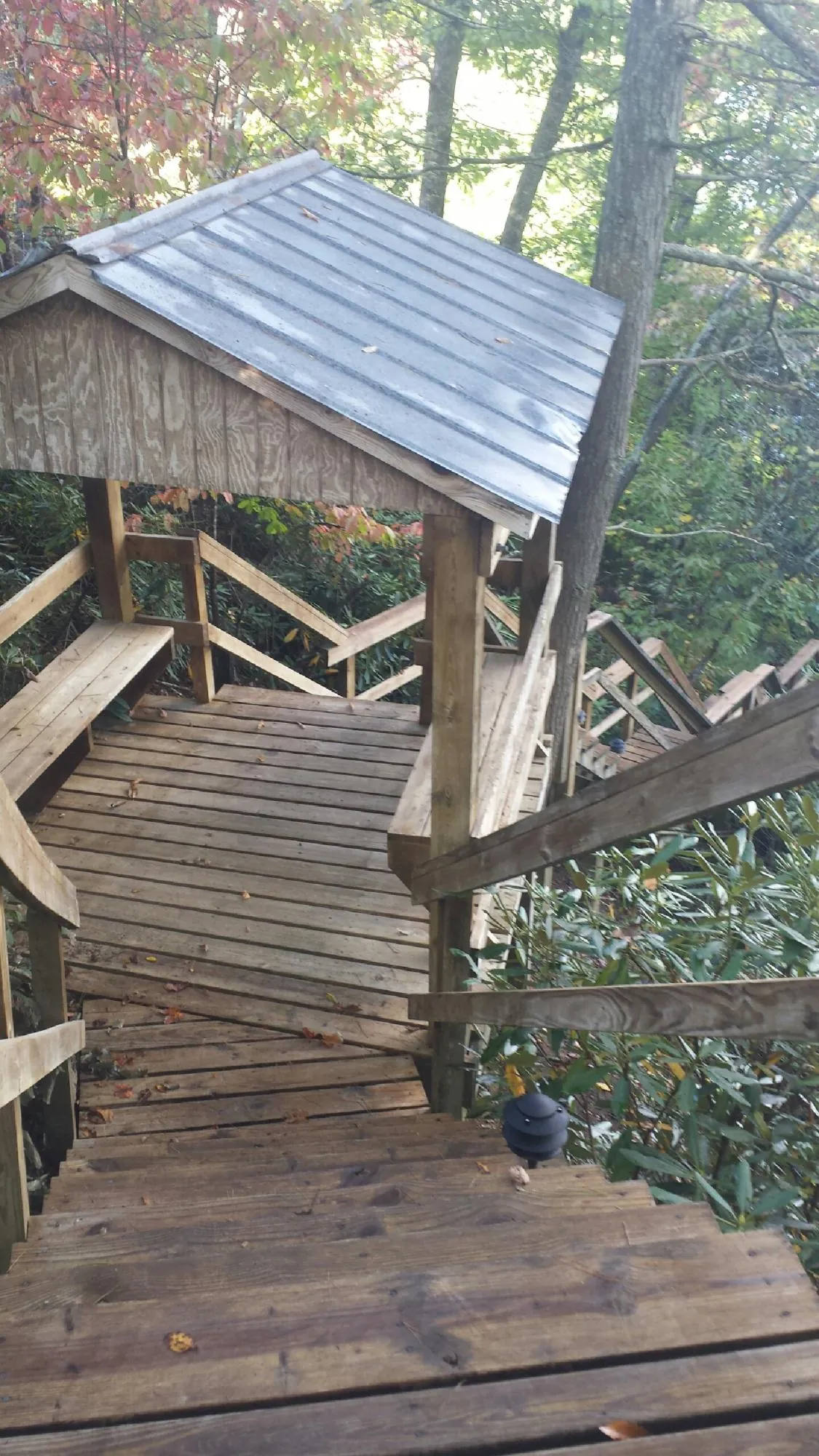Metal roofed shelter over wooden steps on a wooded walkway — Skylight Repair & Installation work by our crew in Wyndmere