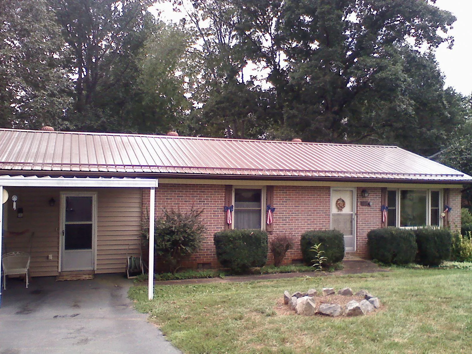 Bronze metal roof and carport on a brick ranch home — Roof Repair work by our crew in Wyndmere
