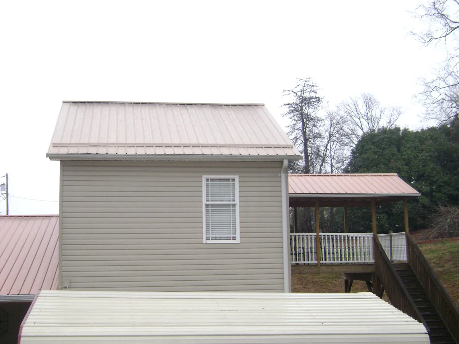 Tan metal roofs on a two story addition and attached porch, from a Roof Replacement job in Wyndmere